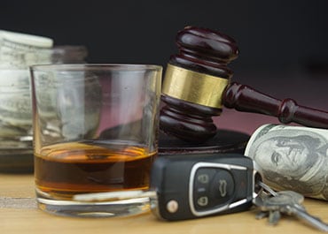 Glass of whiskey, car keys, cash, and a gavel, representing DUI Conviction